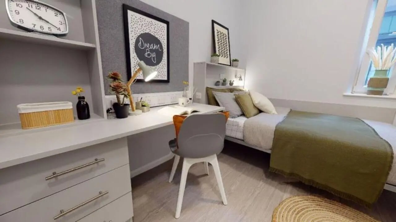 Desk with chair bed and clock bedroom at iQ Will Wyatt Court in London Student Accommodation