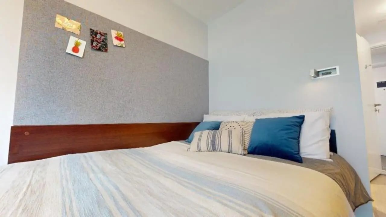Bed with blue pillows and artwork bedroom at iQ Highbury in London Student Accommodation