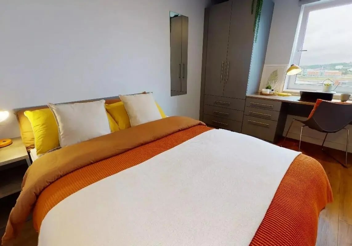 Bed with yellow white pillows desk wardrobe bedroom at iQ Collingwood in Newcastle Upon Tyne Student Accommodation