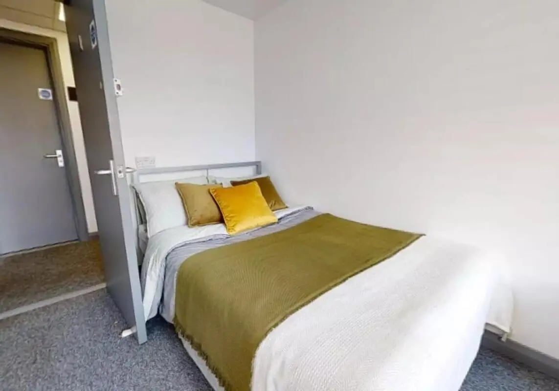 Bed with pillows and green throw Bedroom at iQ Stephenson House in Newcastle Upon Tyne Student Accommodation