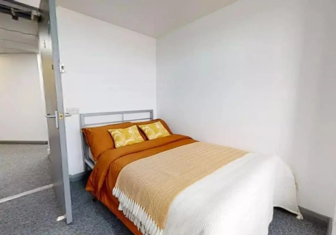 Bed with orange bedding and pillows bedroom at iQ Stephenson House in Newcastle Upon Tyne Student Accommodation