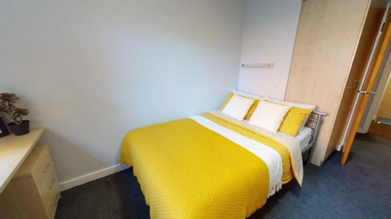 Bed with yellow blanket dresser and wardrobe bedroom at iQ Fiveways House in Wolverhampton Student Accommodation