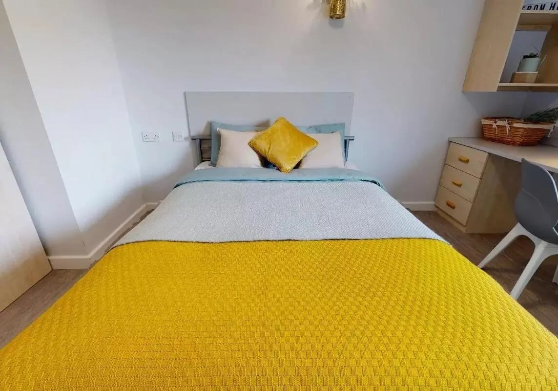 Bed with yellow blanket desk chair bedroom at iQ Wilmslow Park in Manchester Student Accommodation