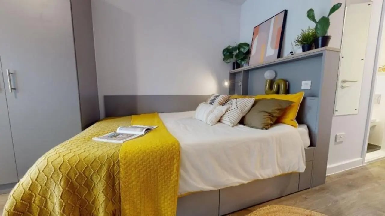 Bed with yellow throw pillows and artwork bedroom at iQ Nelson Court in Nottingham Student Accommodation