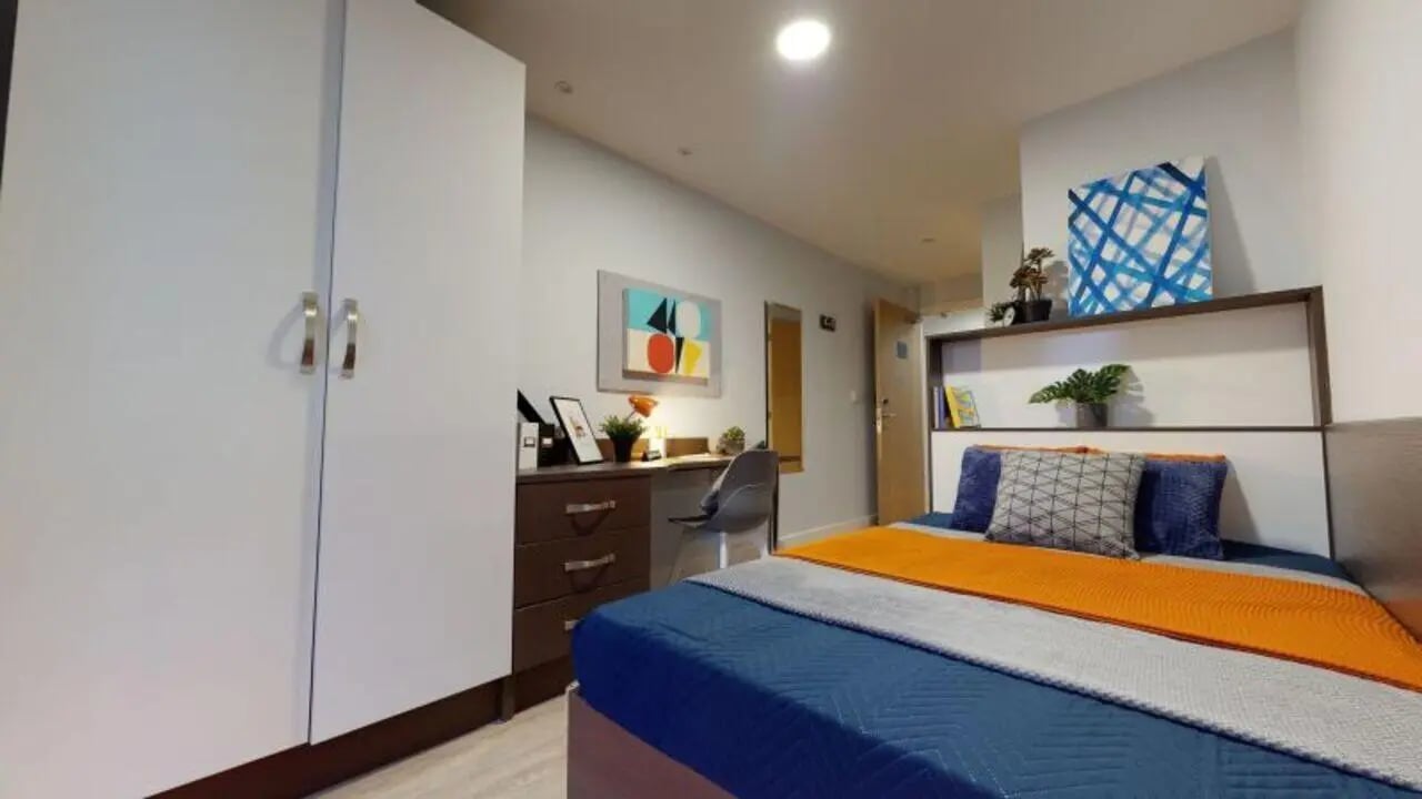 Wardrobe desk bed with orange blue bedding Bedroom at iQ Penworks House in Birmingham Student Accommodation