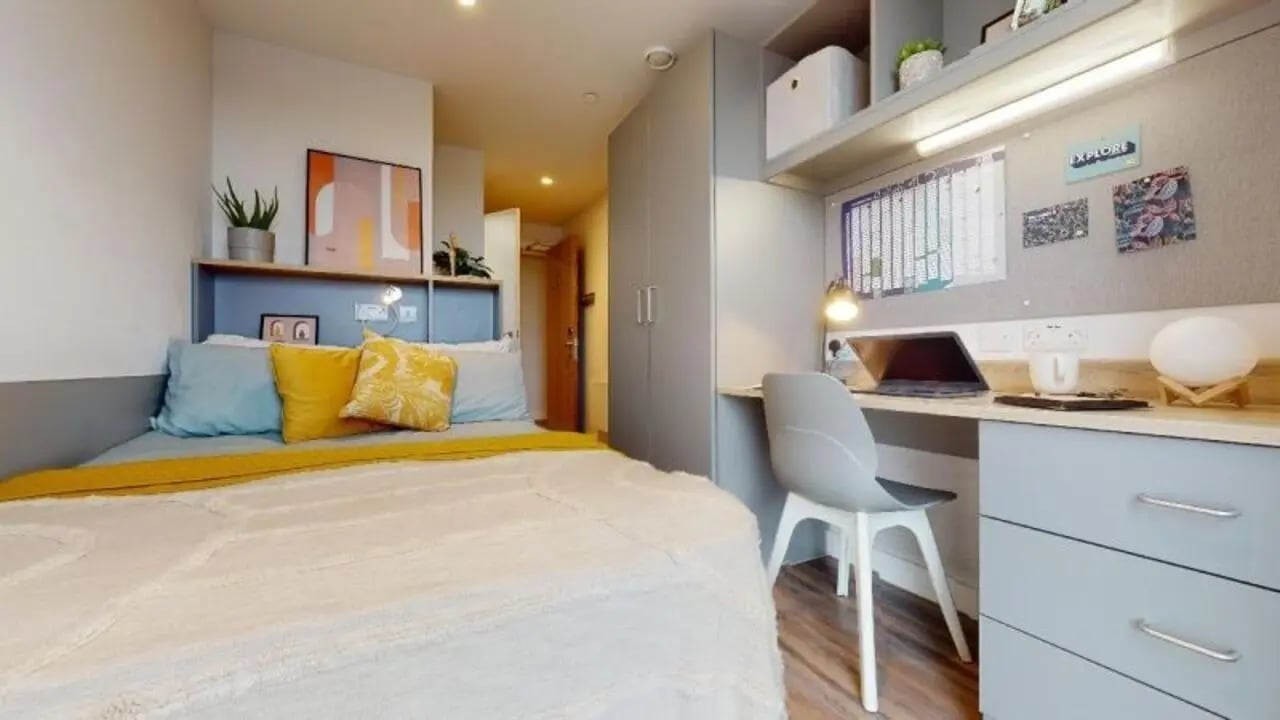 Bed with yellow pillows and desk with laptop bedroom at iQ Weaver Place in Coventry Student Accommodation