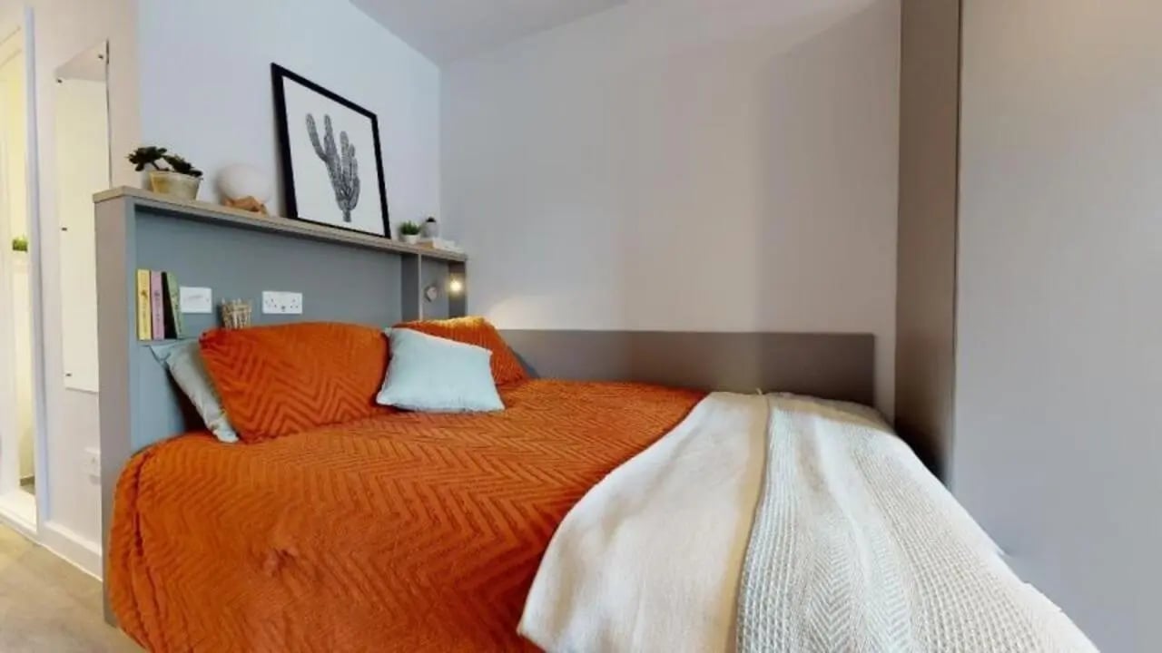 Bed with orange duvet and shelves bedroom at iQ Nelson Court in Nottingham Student Accommodation