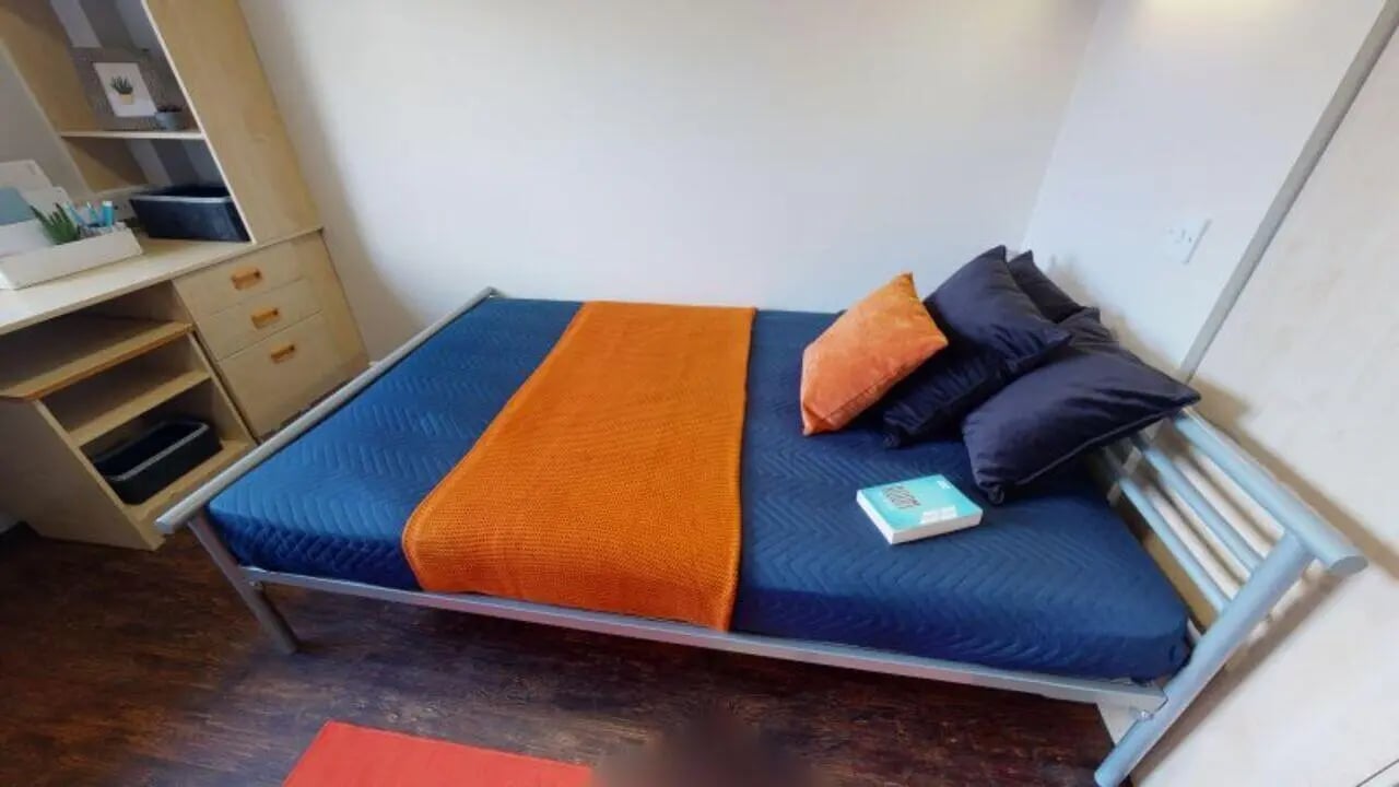 Blue bed with orange blanket and pillows bedroom at iQ Grosvenor House in Leicester Student Accommodation