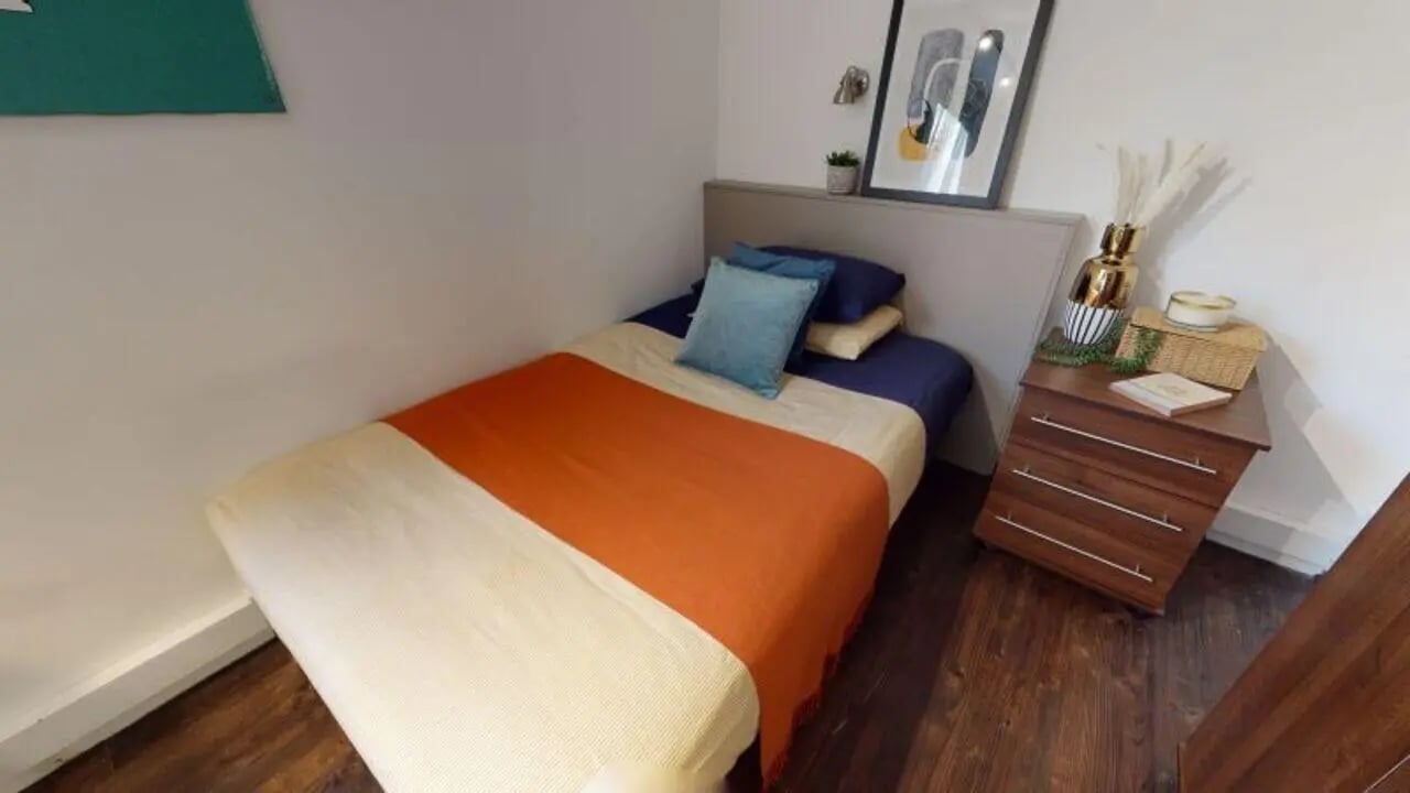Bed with orange throw pillows and nightstand bedroom at iQ Grosvenor House in Leicester Student Accommodation