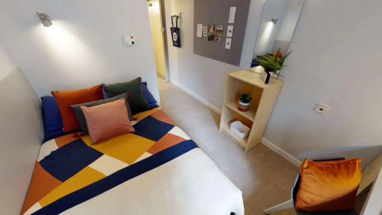 Bed with colorful pillows and shelf bedroom at iQ Great Newton House in Liverpool Student Accommodation