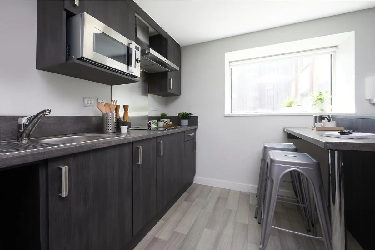 Modern kitchen with microwave sink stools and window kitchen at Collegiate Tower in Bristol Student Accommodation