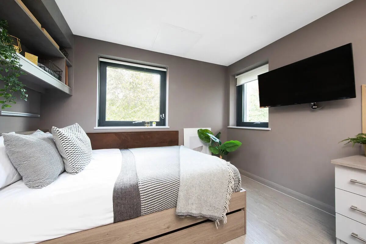Bed with patterned pillows modern TV and shelves bedroom at Collegiate Eclipse in Cardiff Student Accommodation