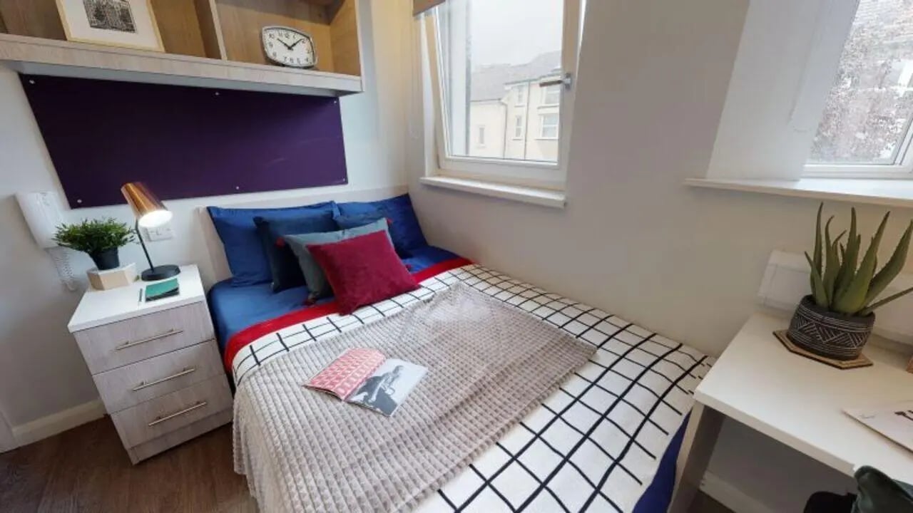 Bed with blue pillows bedside table lamp bedroom at iQ Sawmills in Brighton Student Accommodation