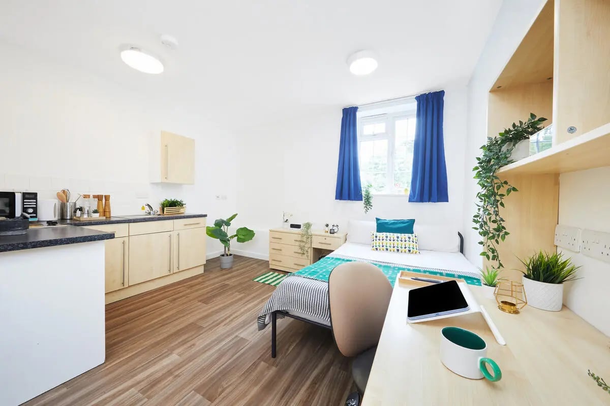 Bed desk kitchen and plants studio apartment at Collegiate Bonhay House in Exeter Student Accommodation