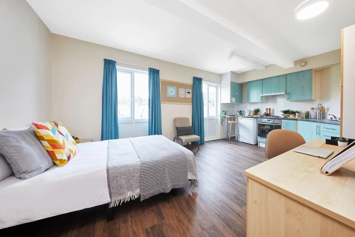 Bed desk kitchen with blue cabinets studio apartment at Point Exe Exeter in Exeter Student Accommodation