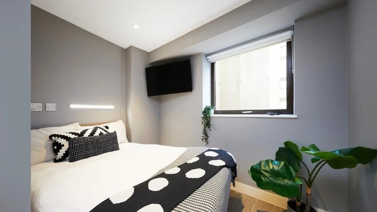 Bed with patterned pillows and blanket bedroom at Collegiate Nova in Nottingham Student Accommodation
