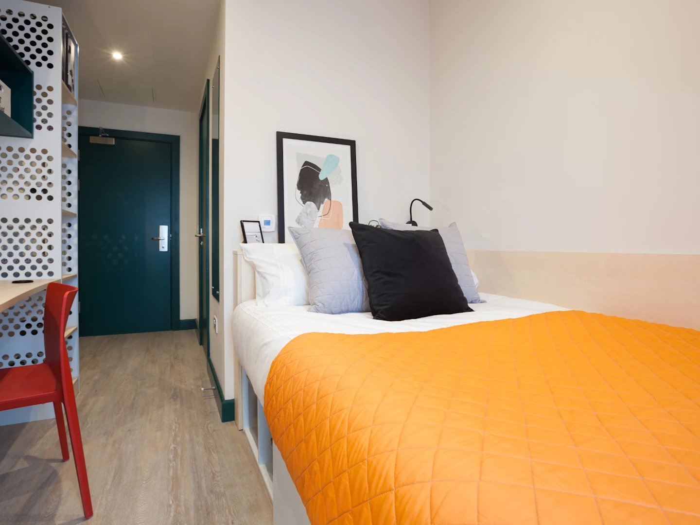 Bed with orange quilt and artwork bedroom at Highlight Parkgate in Dublin Student Accommodation