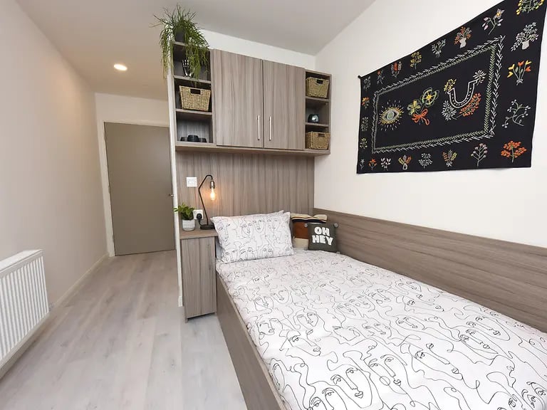 Bed with face print bedding and wall art bedroom at Melbourn Point in Cork Student Accommodation