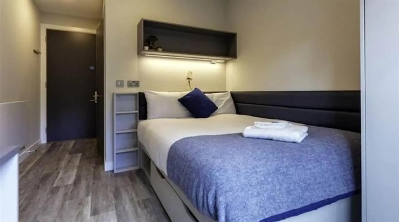 Bed with blue blanket and shelves bedroom at The Westwood in Galway Student Accommodation