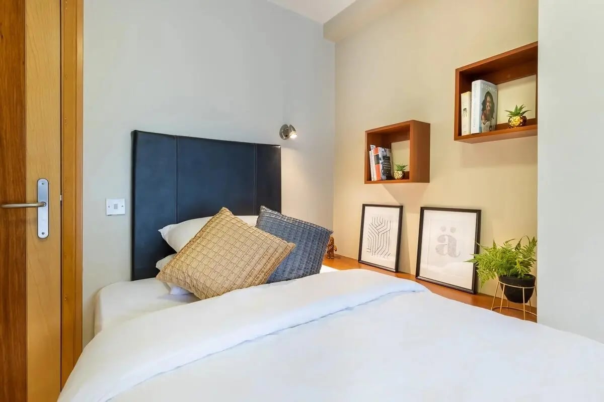 Bed with pillows shelves books art and plant bedroom at Cuirt na Coiribe in Galway Student Accommodation