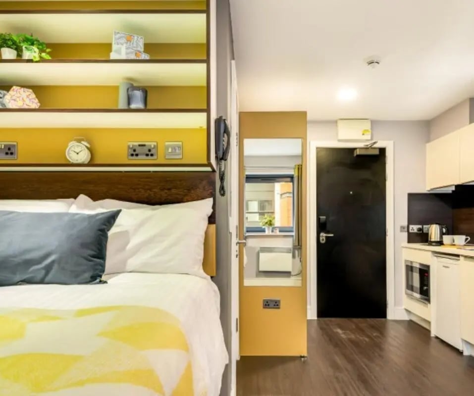 Bed with shelves and kitchen area studio at The Edge - Leeds in Leeds Student Accommodation