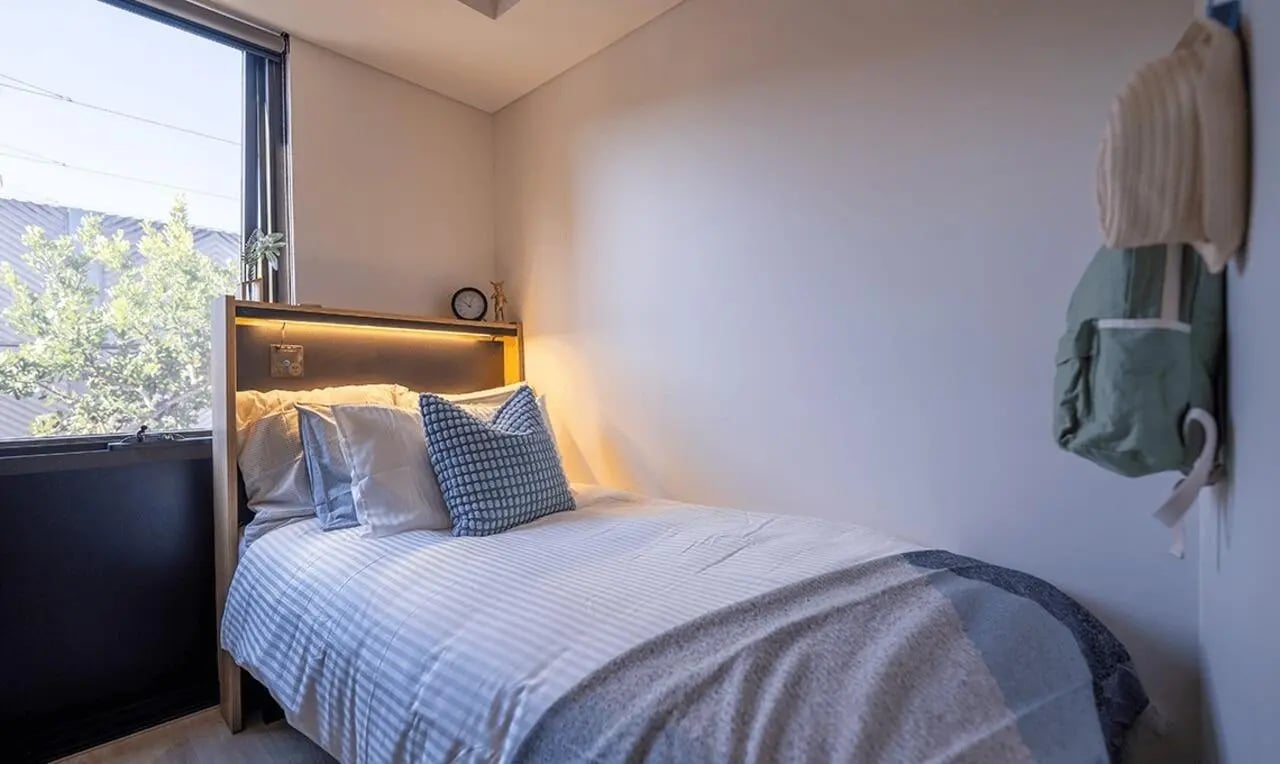 Bed pillows clock backpack bedroom at The Switch Kensington in Sydney Student Accommodation