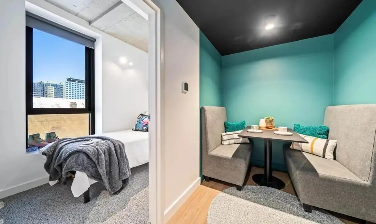 Bed with blanket and desk with seating bedroom dining area at Perth Central in Perth Student Accommodation