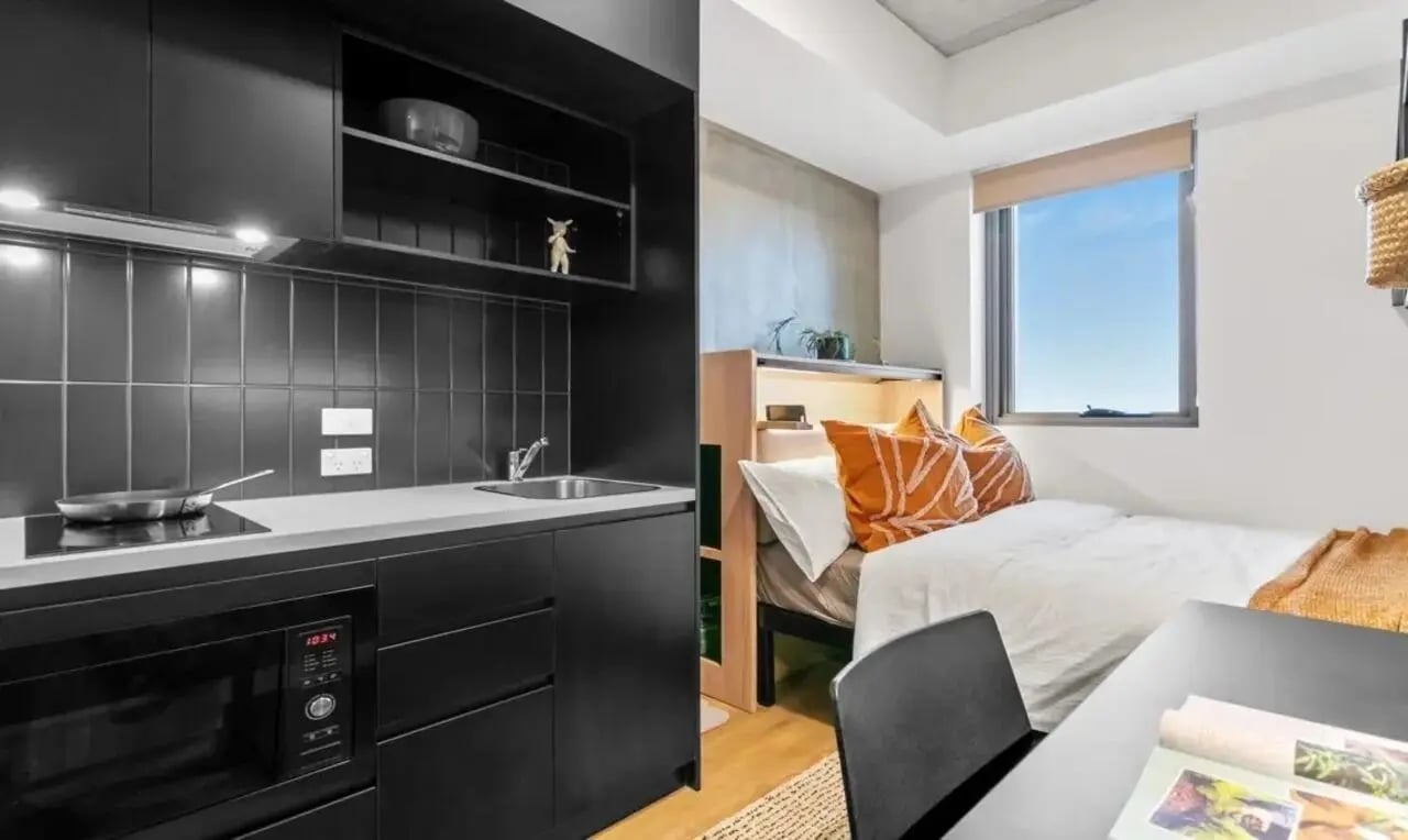 Black kitchen area and single bed bedroom at The Switch Adelaide in Adelaide Student Accommodation
