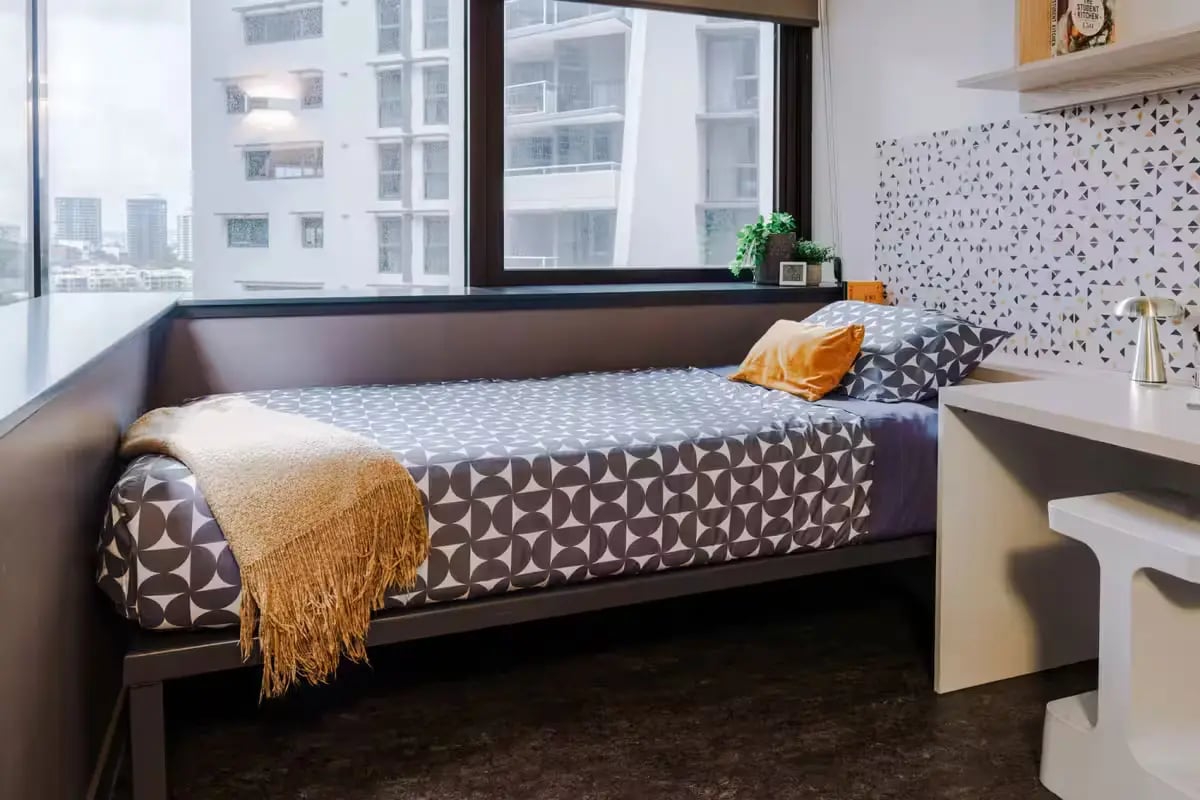 Bed with patterned bedding and desk Bedroom at Student One Adelaide Street in Brisbane Student Accommodation