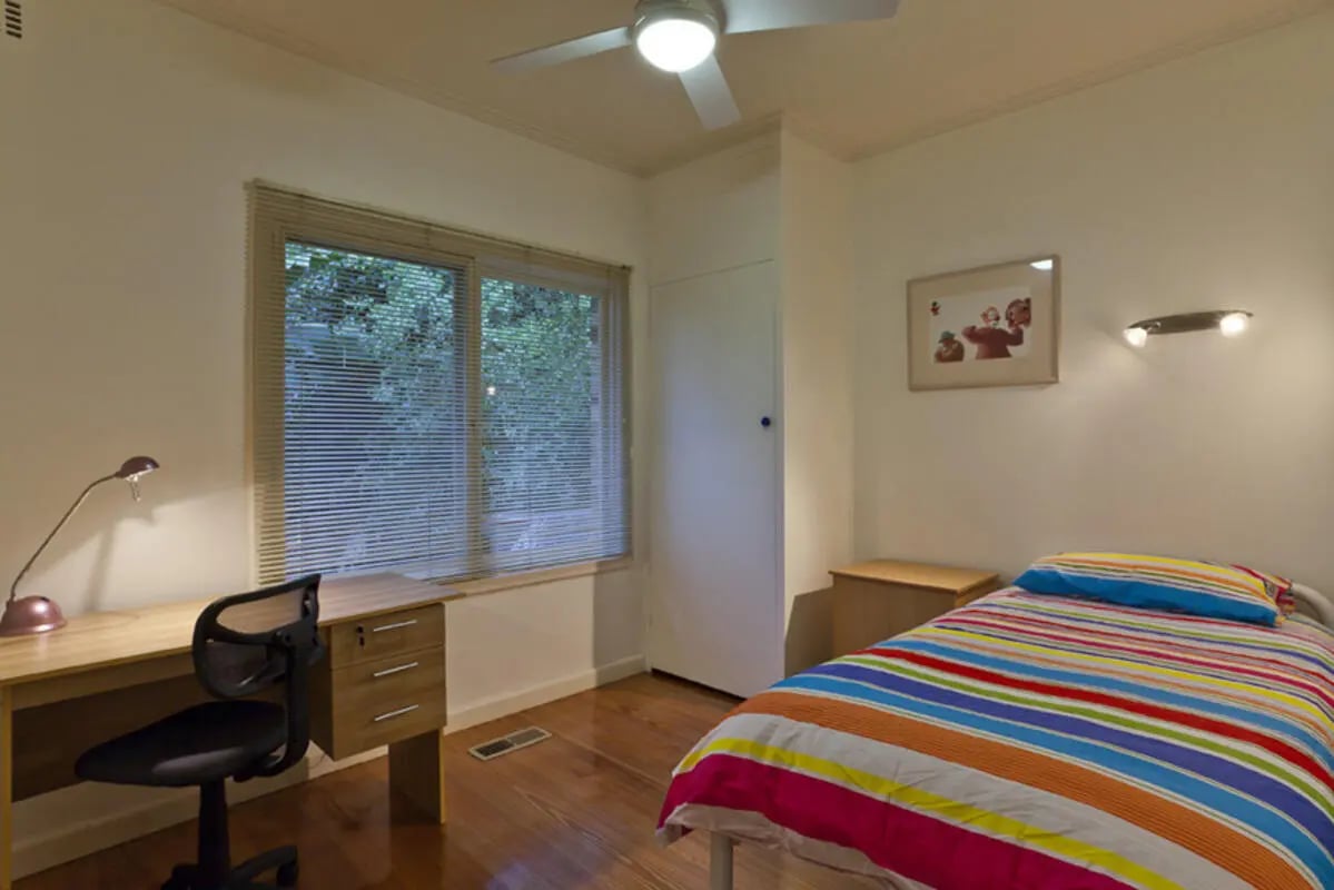 Desk chair bed with striped comforter bedroom at Park Lane House in Melbourne Student Accommodation