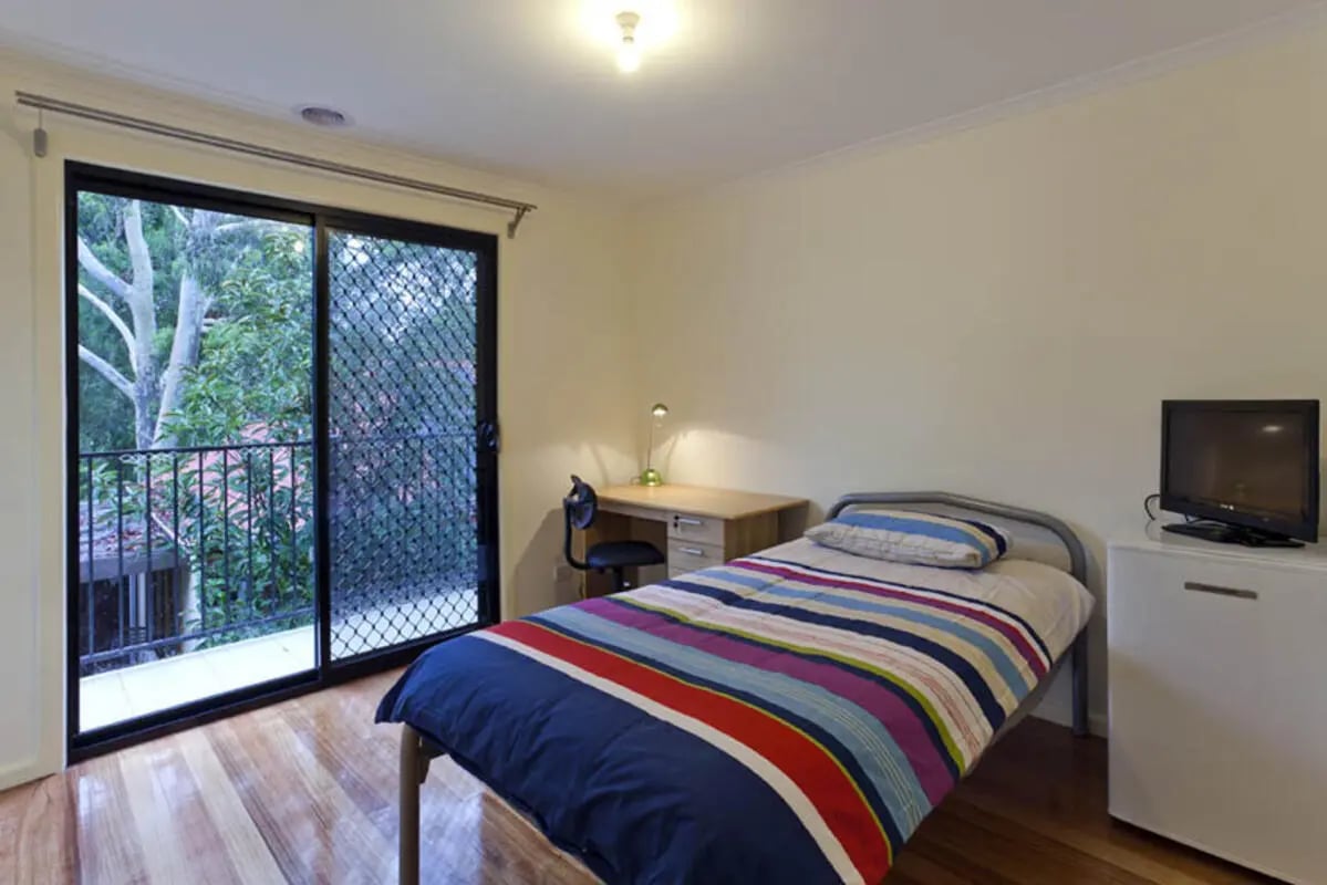 Bed desk chair TV and sliding door bedroom at Park Lane House in Melbourne Student Accommodation