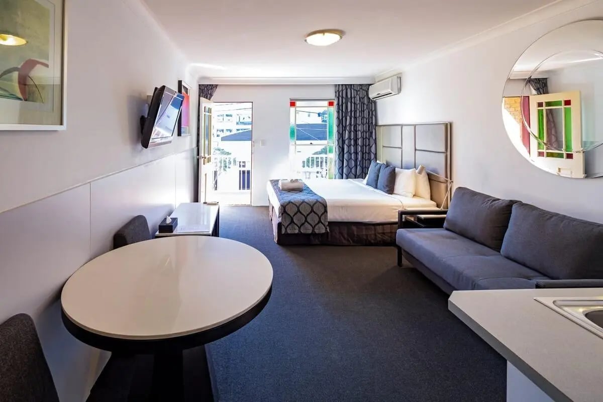 Bed couch table TV and kitchen living room at ume Redfern Village in Sydney Student Accommodation