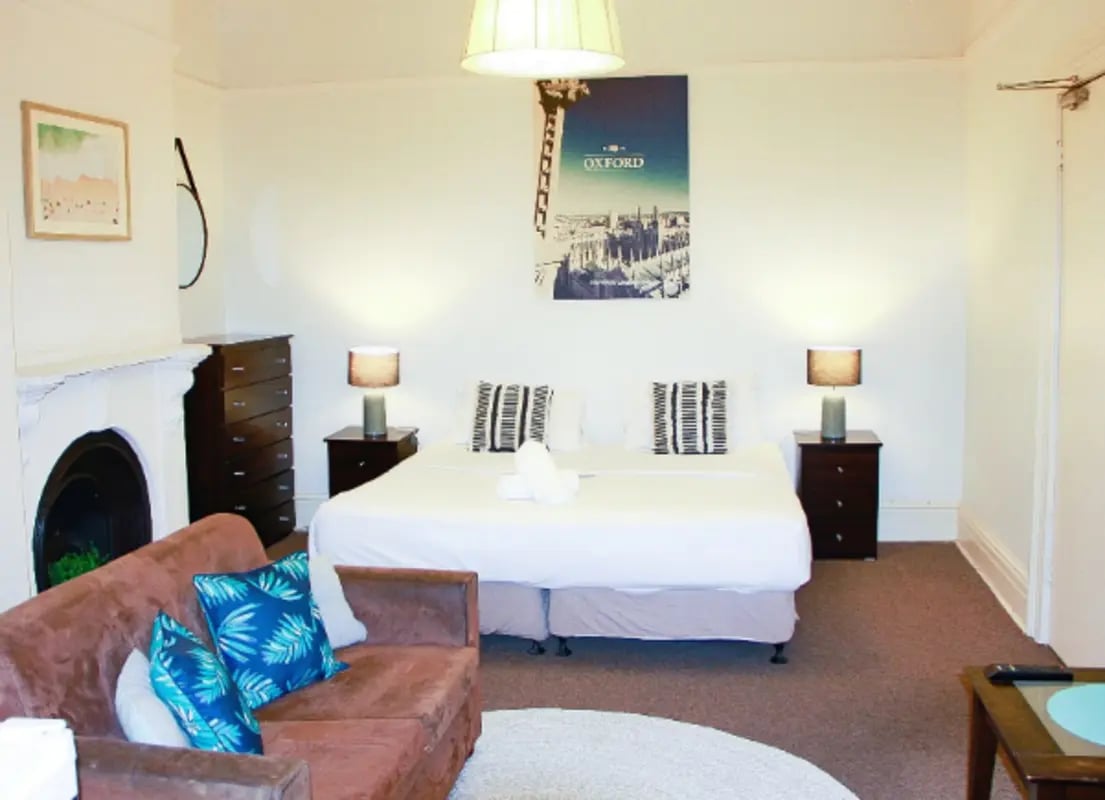 Brown sofa bed lamps chest of drawers bedroom at ume 152 Darlinghurst Village in Sydney Student Accommodation