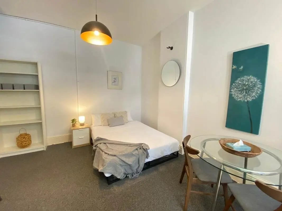 Bed bookshelf mirror dining table bedroom at ume 148 Darlinghurst Village in Sydney Student Accommodation