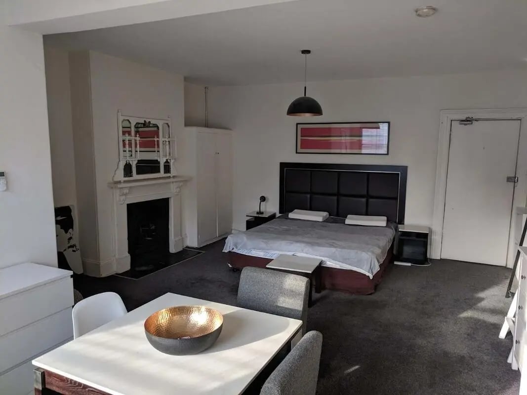Bed fireplace wardrobe table chairs bedroom at ume 148 Darlinghurst Village in Sydney Student Accommodation