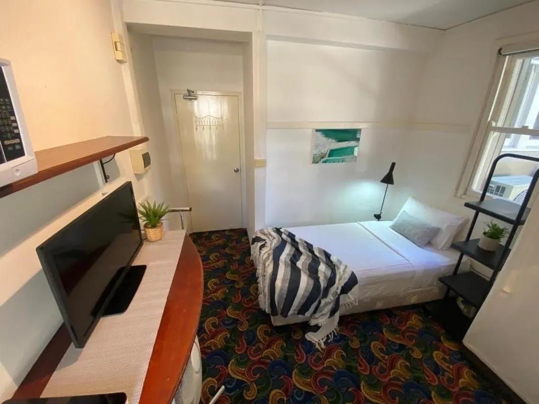 Bed TV shelf and door bedroom at ume 148 Darlinghurst Village in Sydney Student Accommodation