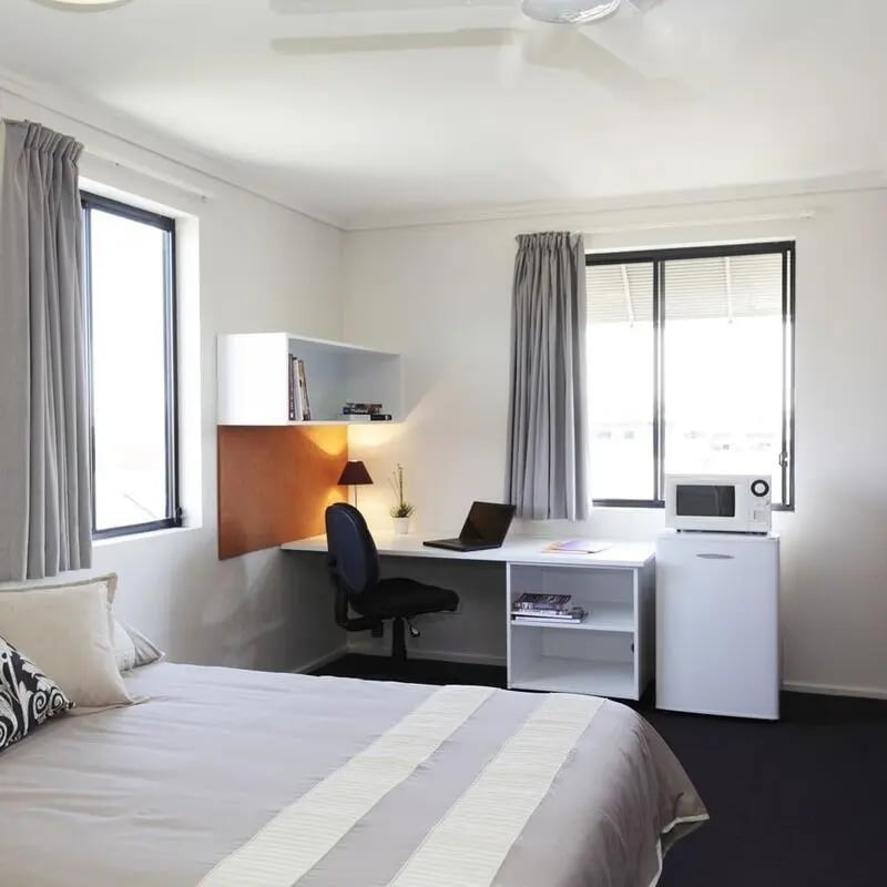 Bed desk chair laptop microwave and mini-fridge bedroom at Sydney University Village in Sydney Student Accommodation