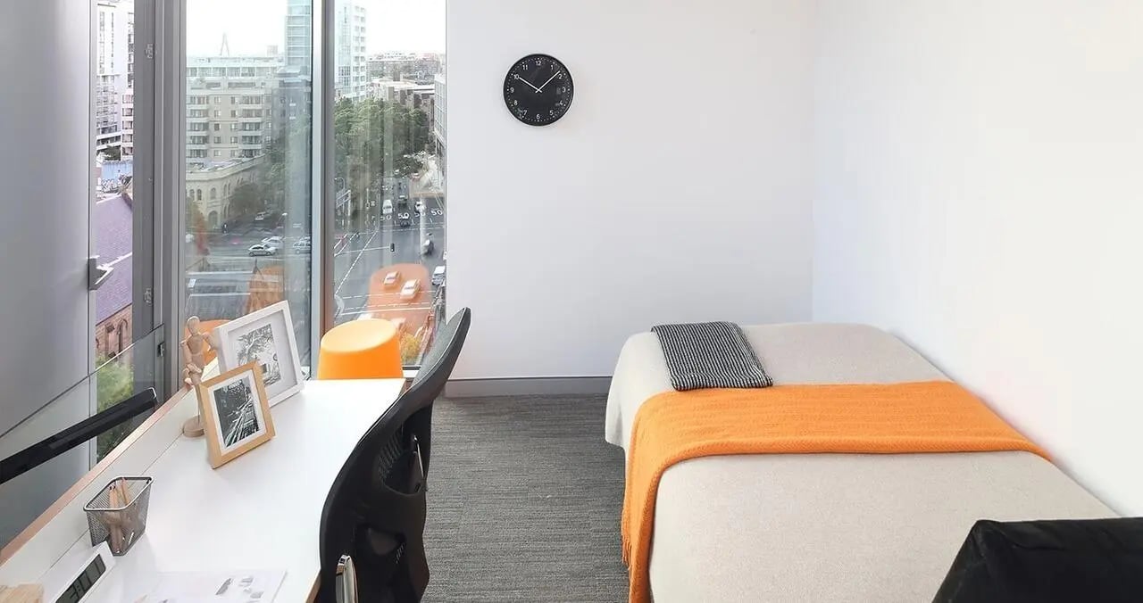 Bed desk chair clock and window bedroom at Iglu Central in Sydney Student Accommodation