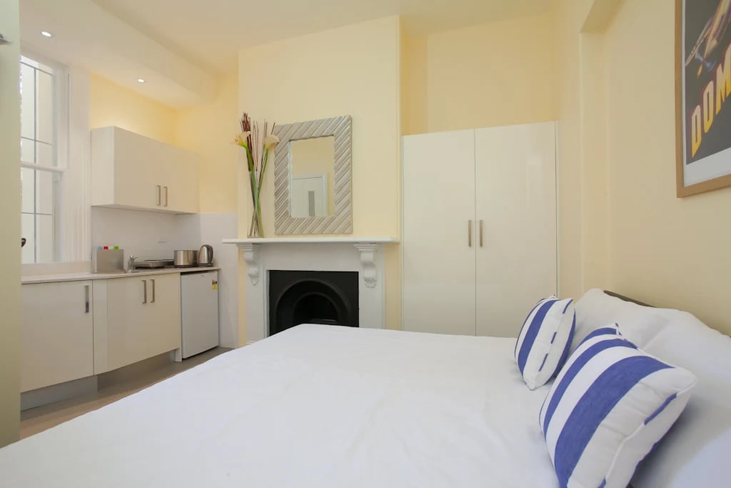 Kitchenette fireplace wardrobe with bed and pillows Bedroom at ume 142 Darlinghurst Village in Sydney Student Accommodation