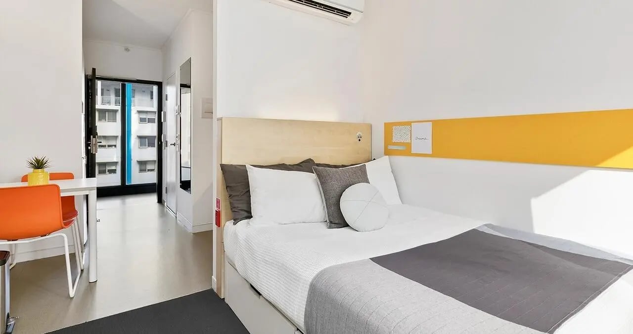 Bed dining table with orange chairs bedroom at Iglu Chatswood in Sydney Student Accommodation