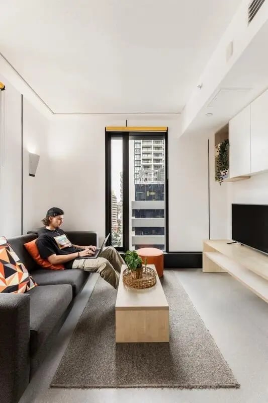 Man on couch with laptop living room at Iglu Brisbane City in Brisbane Student Accommodation