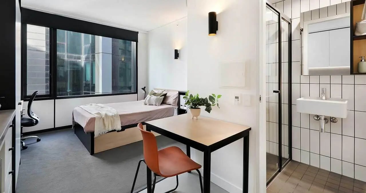 Bed desk chair plant and bathroom bedroom at Iglu Melbourne City in Melbourne Student Accommodation