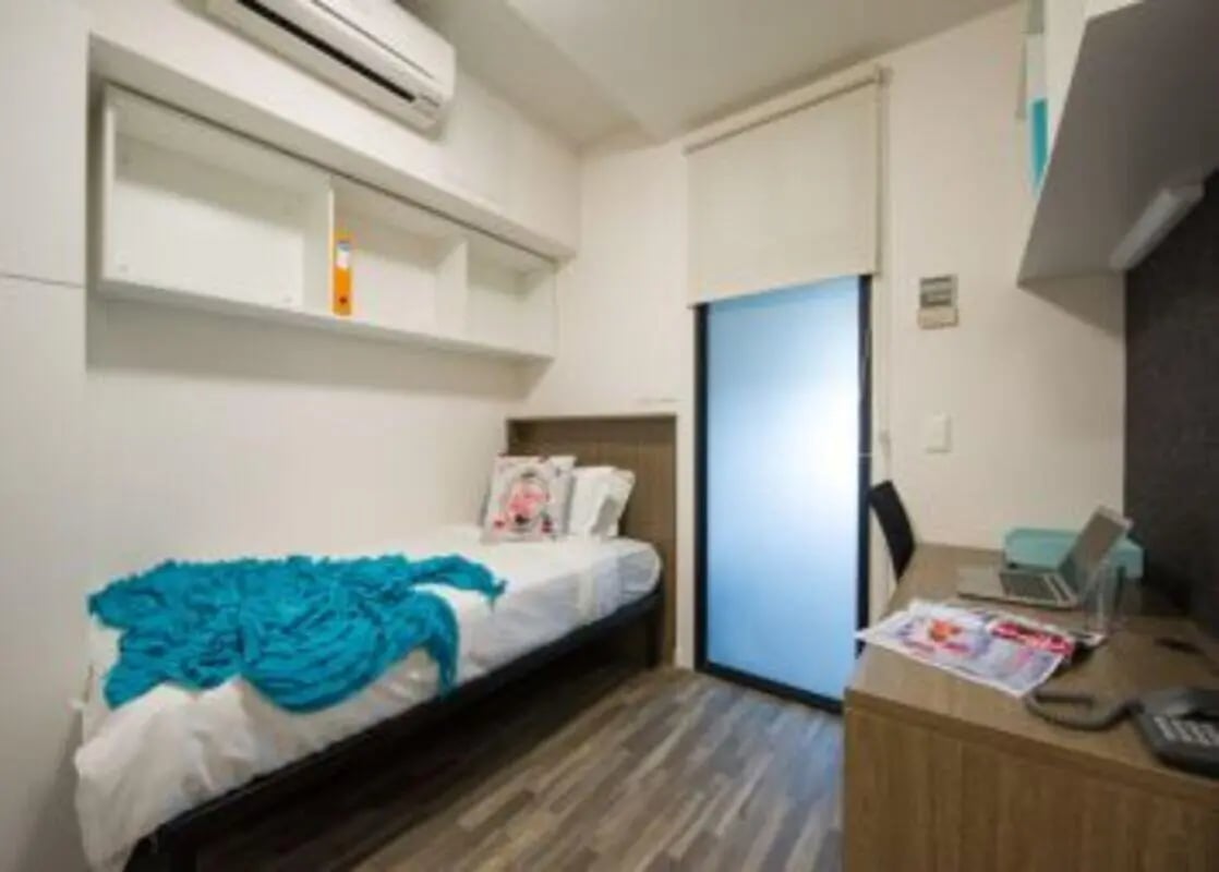 Bed with blue throw desk and laptop bedroom at UniLodge Darwin in Darwin Student Accommodation