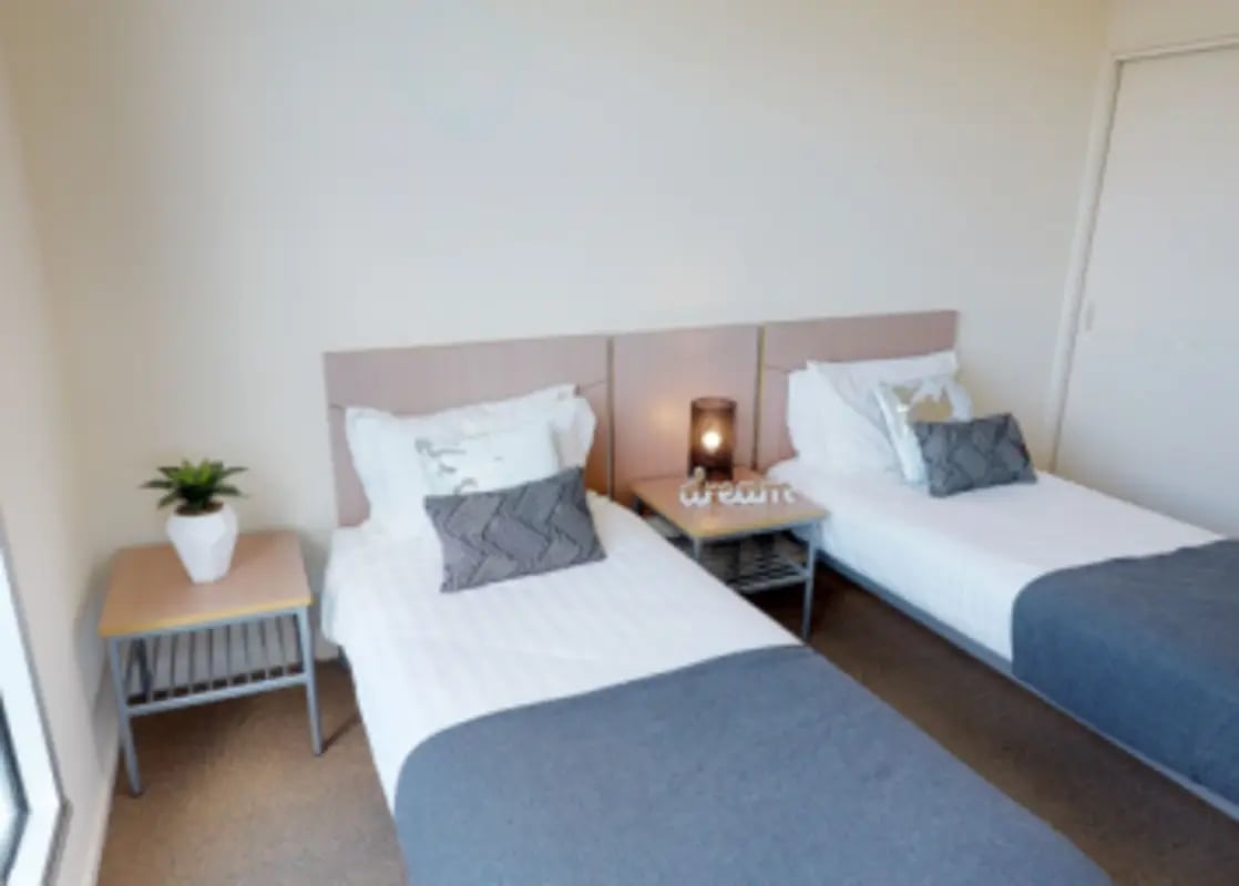 Two beds nightstands with plant and lamp bedroom at Student Living - 800 Swanston in Melbourne Student Accommodation