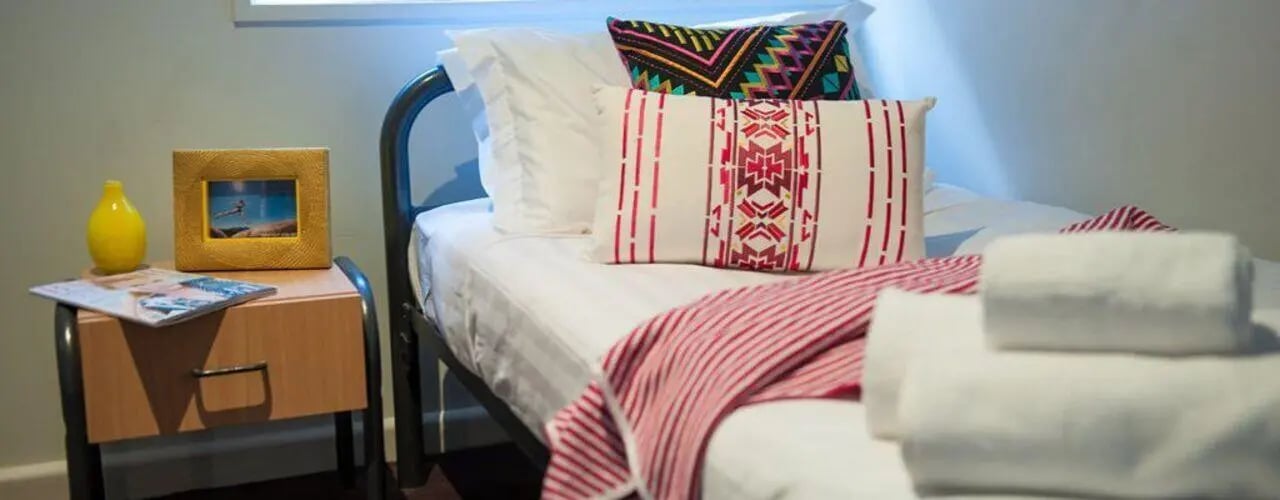 Bed with pillows throws and bedside table bedroom at Student Living-339 Swanston in Melbourne Student Accommodation