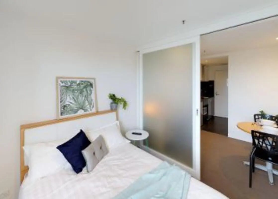 Bed with blue pillows artwork sliding door living room at Student Living on Villiers in Melbourne Student Accommodation