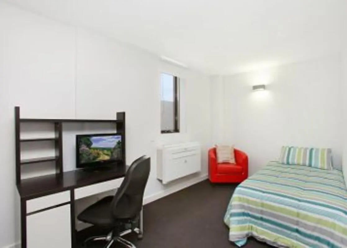 Desk chair television red chair striped bed bedroom at Student Living on Raleigh in Melbourne Student Accommodation
