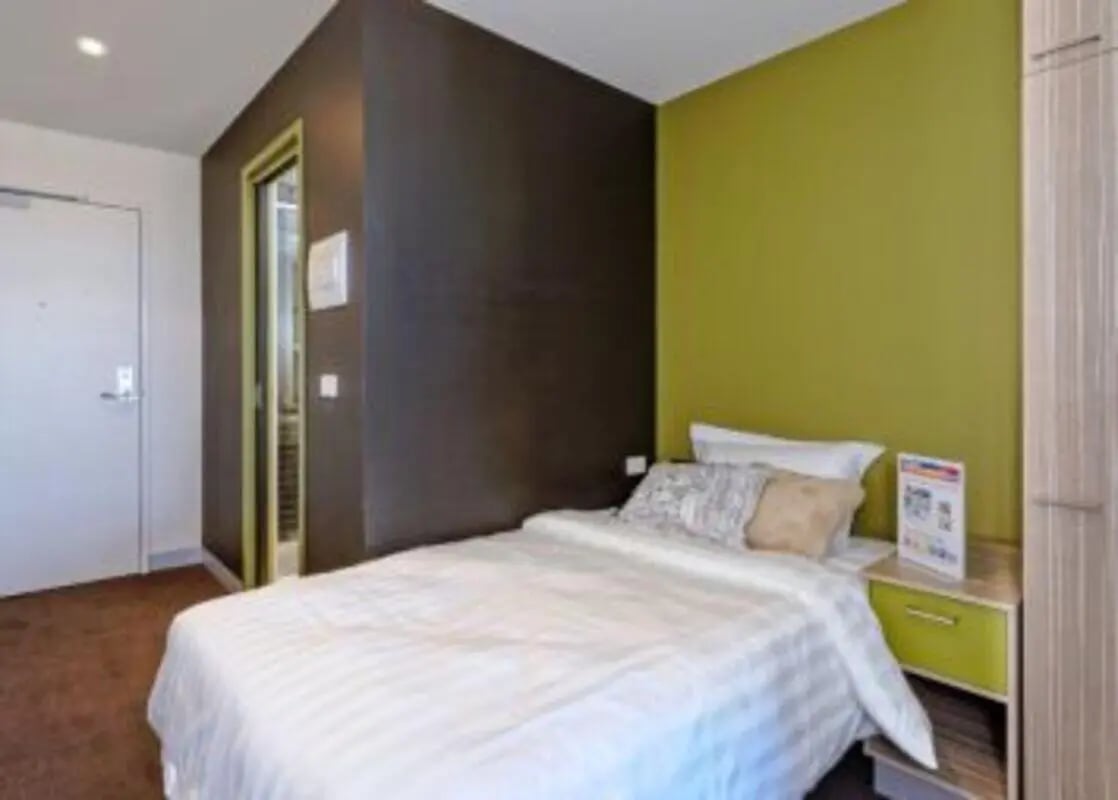 Bed white linens pillows bedside table bedroom at Student Living - Vivida in Melbourne Student Accommodation