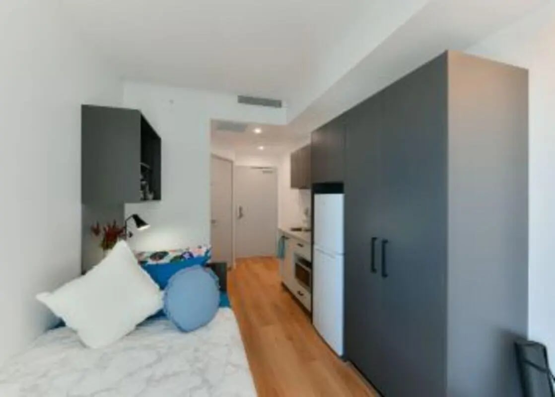 Bed pillows and kitchen visible student accommodation bedroom at UniLodge Toowong in Brisbane Student Accommodation