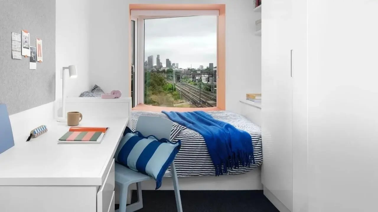 Desk lamp striped pillows bed blue blanket bedroom at Scape Mile End in London Student Accommodation